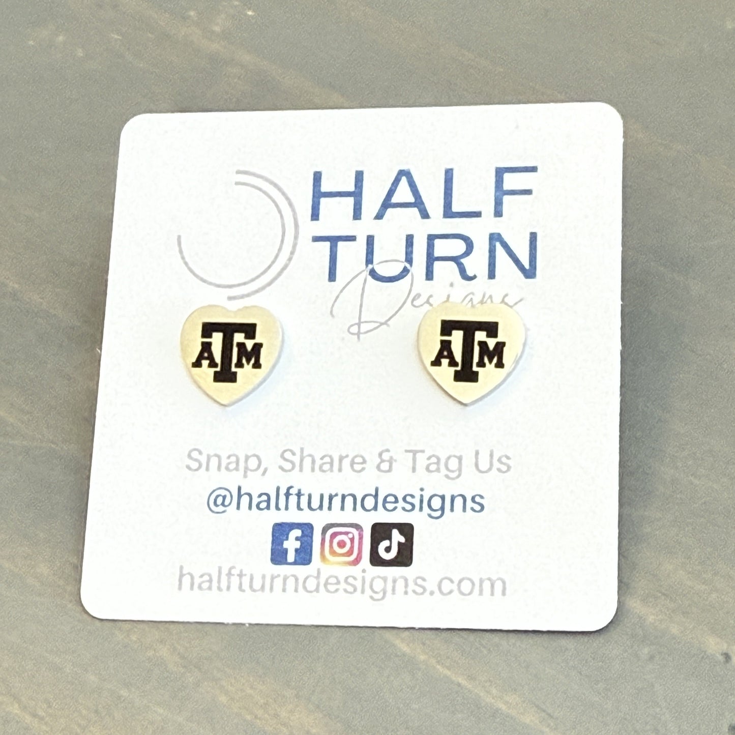 Heart-Shaped Texas A&M Stainless Steel Earring Studs engraved with the Texas A&M logo in gold or silver finish by Half Turn Designs, officially licensed with Texas A&M University.