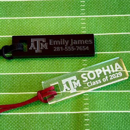 Officially licensed Texas A&M luggage and bag tags in rectangular shape, measuring 2.75x0.75".  These acrylic luggage and bag tags are personalized with 1-2 lines of text and come in 1/8" or 1/4" width.  Luggage tag colors include Clear, Frosted, Opaque Black, Shiny Black, Maroon that engraves white and Black that engraves white.  Shiny Black and Clear options shown here.