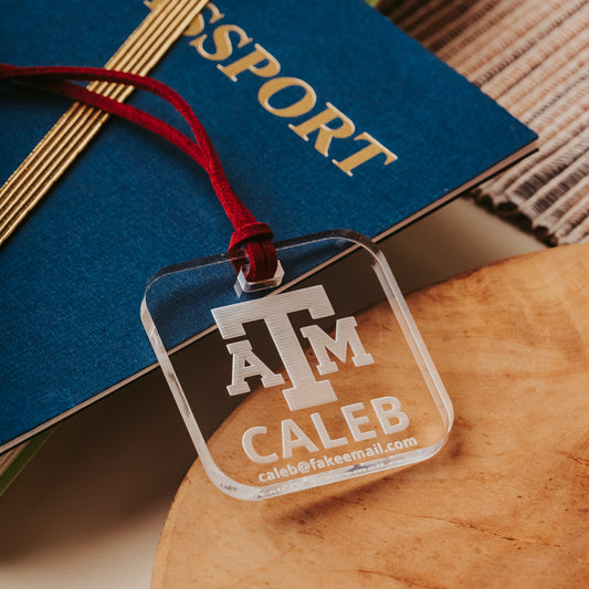 Officially licensed Texas A&M luggage tags in square shape, 2x2".  These acrylic luggage tags are personalized with 1-2 lines of text and come in 1/8" or 1/4" width.  Luggage tag colors include Clear, Frosted, Opaque Black, Shiny Black, Maroon that engraves white and Black that engraves white.  Clear acrylic version shown here.