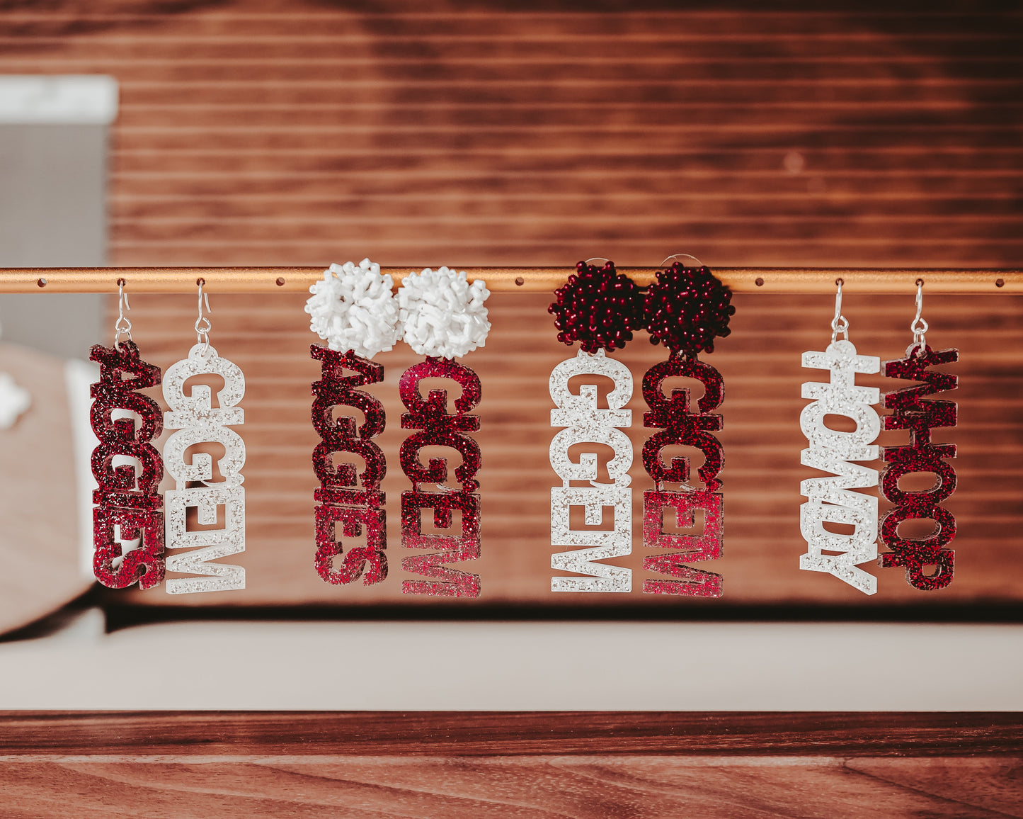 Texas A&M Officially Licensed Mix and Match Dangle Earrings in maroon and white glitter. Create your own pair of earrings combining TAMU phrases like "Aggies", "Gig 'em", "Whoop" and "Howdy" into a pair of earrings with your choice of glitter color and earring topper.