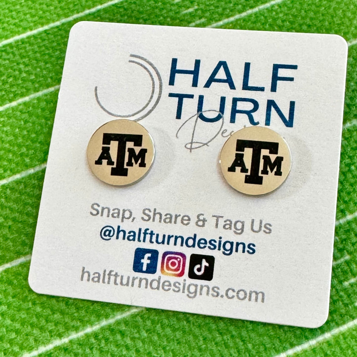 Texas A&M stud earrings engraved with the TAMU logo. The handmade earrings by Half Turn Designs are circular, 12mm in size and made from hypoallergenic Stainless Steel. Shown here in silver finish.