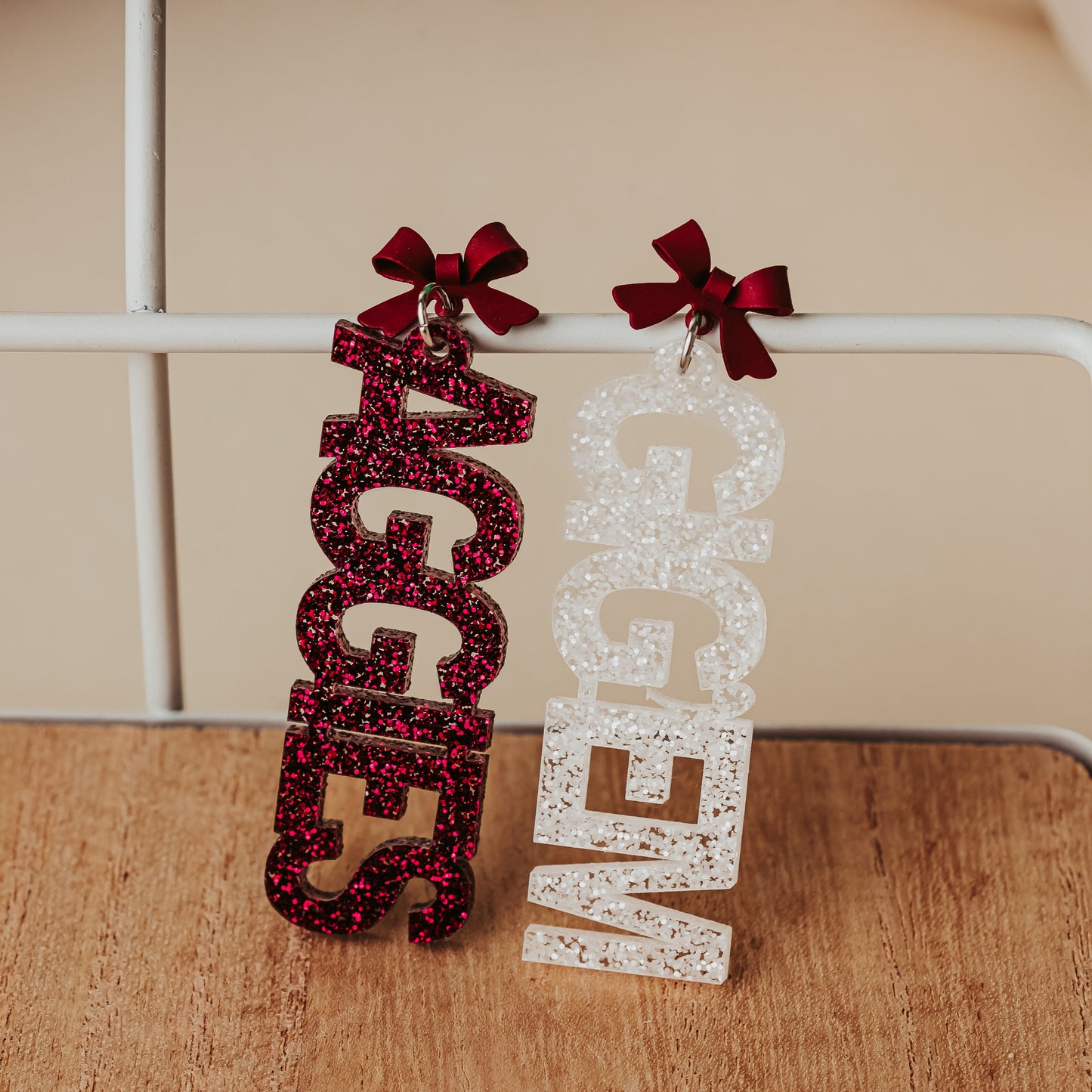 Officially licensed Texas A&M Gig 'Em Aggies maroon and white glitter acrylic earrings with maroon bow stud topper.