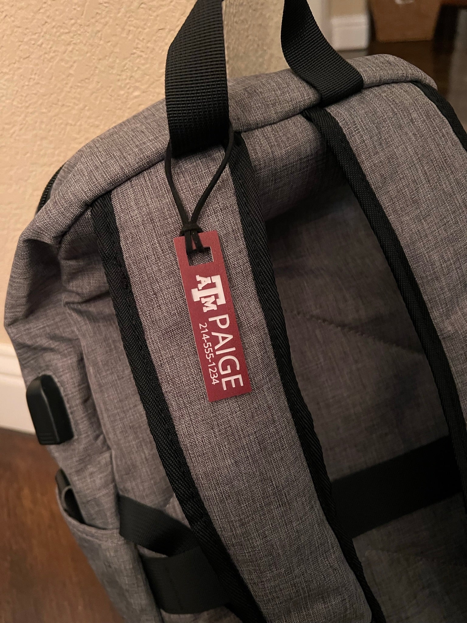 Officially licensed Texas A&M luggage and bag tags in rectangular shape, measuring 2.75x0.75".  These acrylic luggage and bag tags are personalized with 1-2 lines of text and come in 1/8" or 1/4" width.  Luggage tag colors include Clear, Frosted, Opaque Black, Shiny Black, Maroon that engraves white and Black that engraves white.  Maroon that engraves white shown here fastened to a backpack