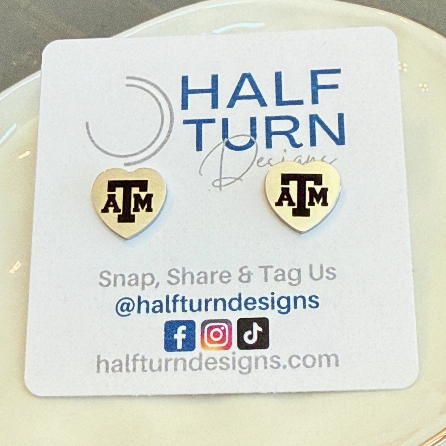 Heart-Shaped Texas A&M Stainless Steel Earring Studs engraved with the Texas A&M logo in gold or silver finish by Half Turn Designs, officially licensed with Texas A&M University.