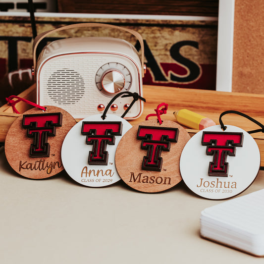 Texas Tech Double T ornament shown in White, Cherry, Walnut and Mahogany wood finishes, each personalized with a name and year
