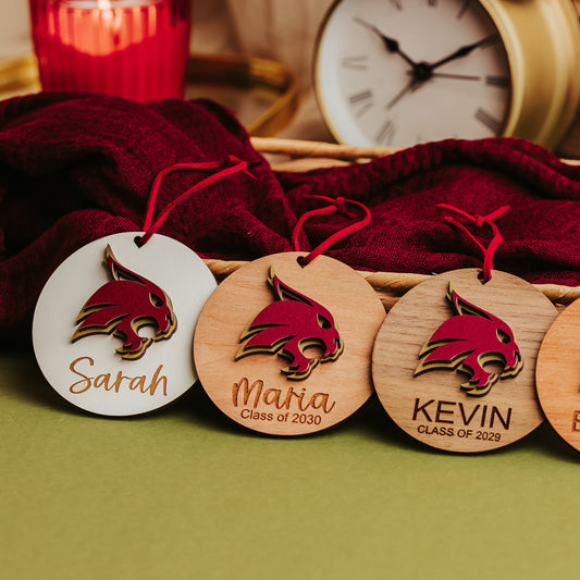 Three Texas State Bobcat ornaments in white, cherry and walnut wood with layered maroon and gold Bobcats and engraved names