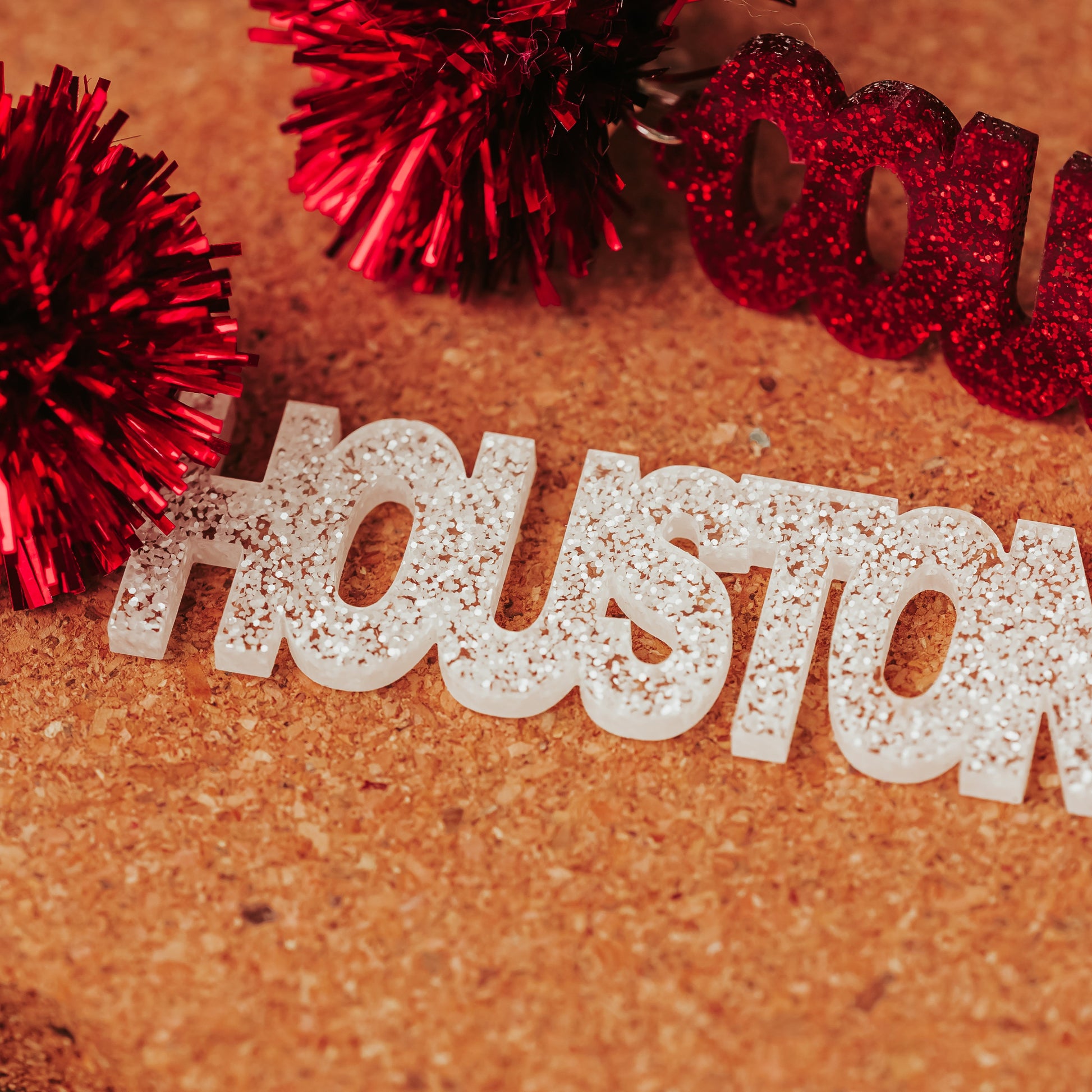 Close up image of Officially Licensed University of Houston Cougars acrylic dangle earrings in red and white glitter with tinsel earring toppers by Half Turn Designs.