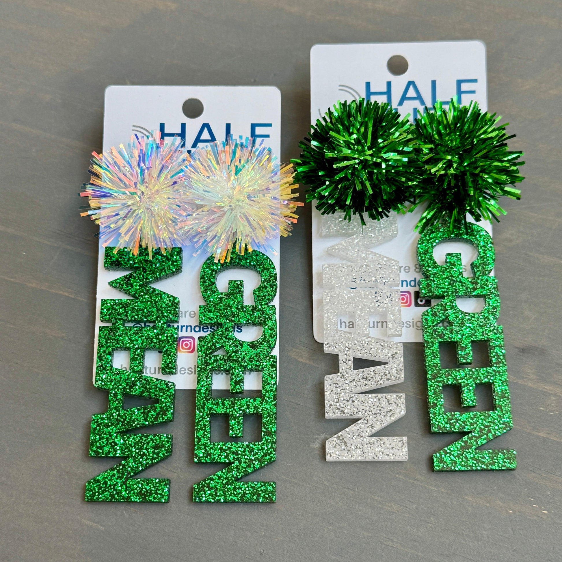 Officially licensed University of North Texas Mean Green Game Day earrings in green and white glitter with your choice of earrings topper including silver earring hooks, rhinestone topper, white tube bead topper, green tinsel topper, iridescent tinsel topper or white tinsel topper.  Mean and Green earrings shown here in green glitter with silver stainless steel earring hooks.  Shown here are mean green earrings with iridescent and green tinsel earring toppers.