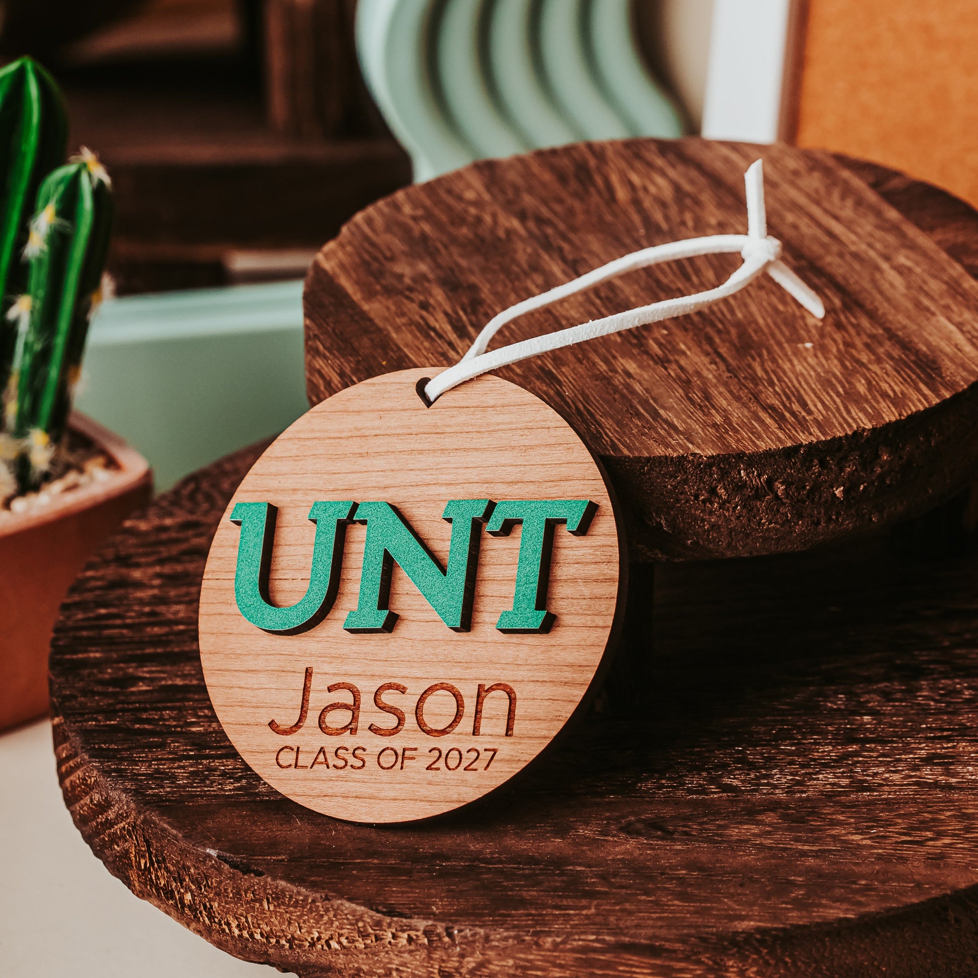 University of North Texas ornaments featuring green UNT letters with engraved personalization in Cherry. Officially licensed Mean Green personalized ornament by Half Turn Designs.