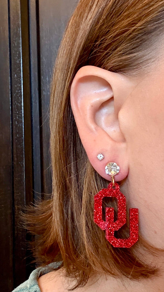Model wearing Officially Licensed University of Oklahoma Sooners Earrings in Crimson and White Glitter Acrylic, OU logo Boomer Sooner Game Day Jewelry for Students & Alumni in a variety of earring toppers including AB Iridescent Jewel, Rhinestone, Bows or Earring Hooks - all available in gold or silver finish. 