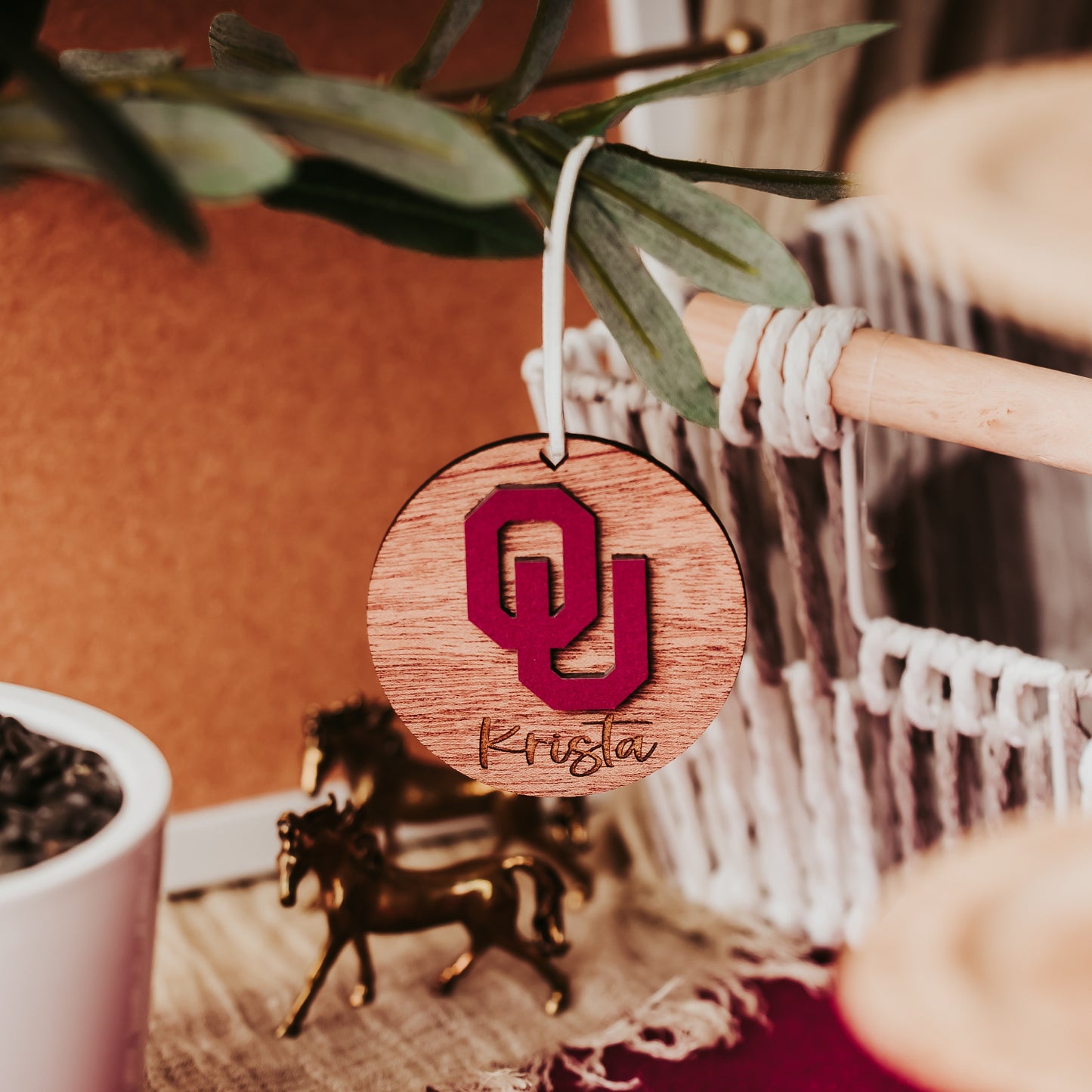 Engraved University of Oklahoma ornament featuring crimson OU logo on 3-inch round wood ornament, customizable with name or phrase, available in Cherry, Mahogany, Walnut, Sapele, or White finishes. Perfect Sooner Christmas gift or car charm. Shown here in Mahogany.