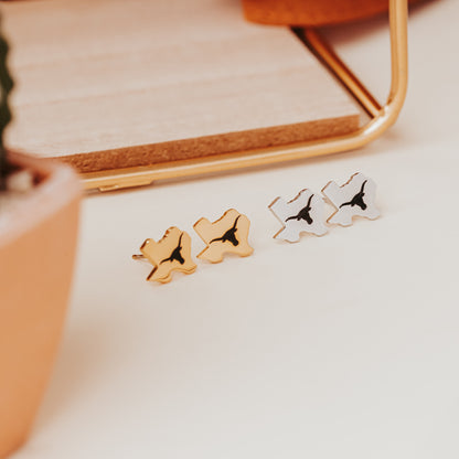 University of Texas stainless steel stud earrings shaped like the state of Texas, engraved with the Longhorn logo. Shown in 12mm size on Half Turn Designs branded earring cards, available in gold and silver finishes.