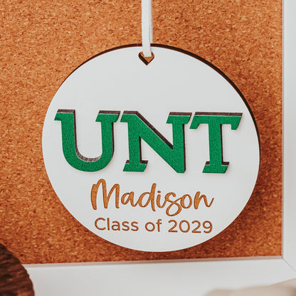 University of North Texas ornaments featuring green UNT letters with engraved personalization in white wood. Officially licensed Mean Green personalized ornament by Half Turn Designs.