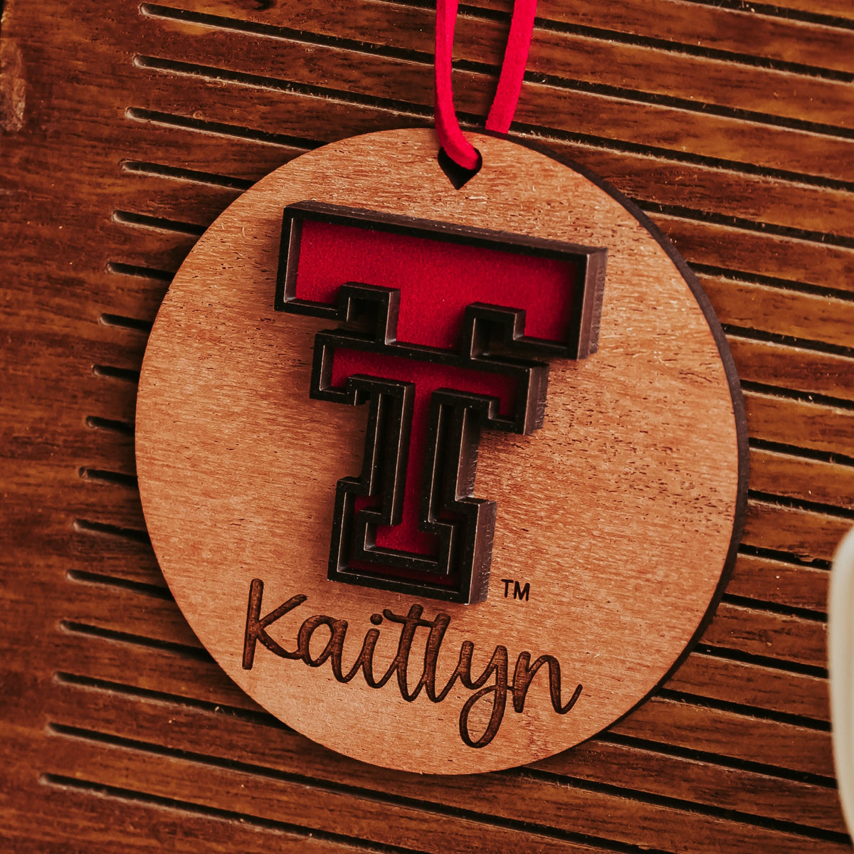 Walnut Texas Tech ornament with a red cord and a red and black Double T logo, personalized with the name Kaitlyn